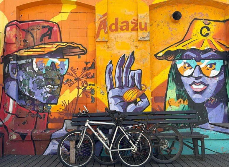 A vibrant mural with abstract figures, a bicycle, and a bench. 1