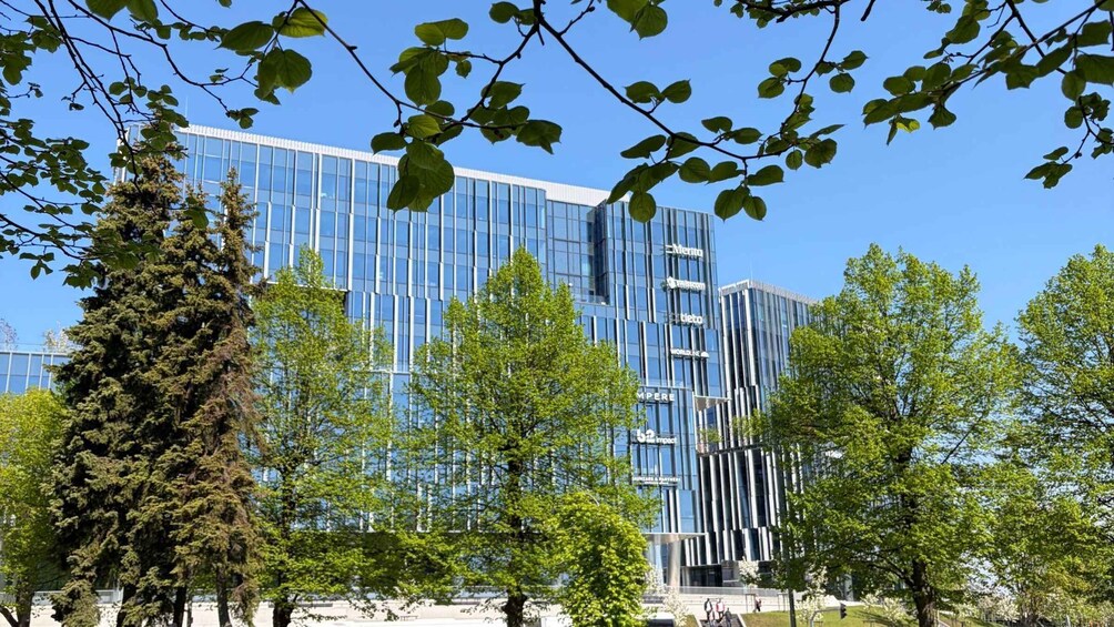 A modern glass building with signage for 'Imperial' and 'Tieto' amidst a park with trees and a clear blue sky. 5