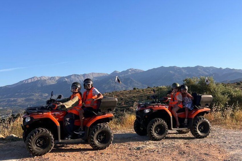 Two people on ATVs in a mountainous area. 1