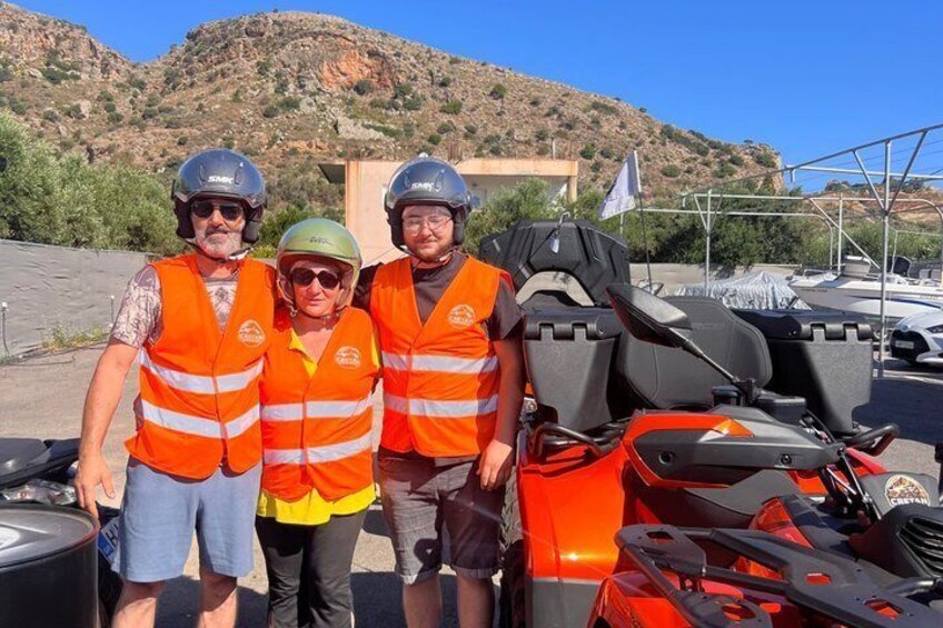 Three people wearing safety vests and helmets, standing next to a red ATV. 2