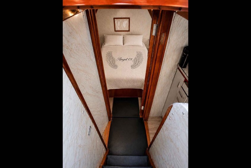 A narrow passageway leading to a bed with a framed picture above it. 3