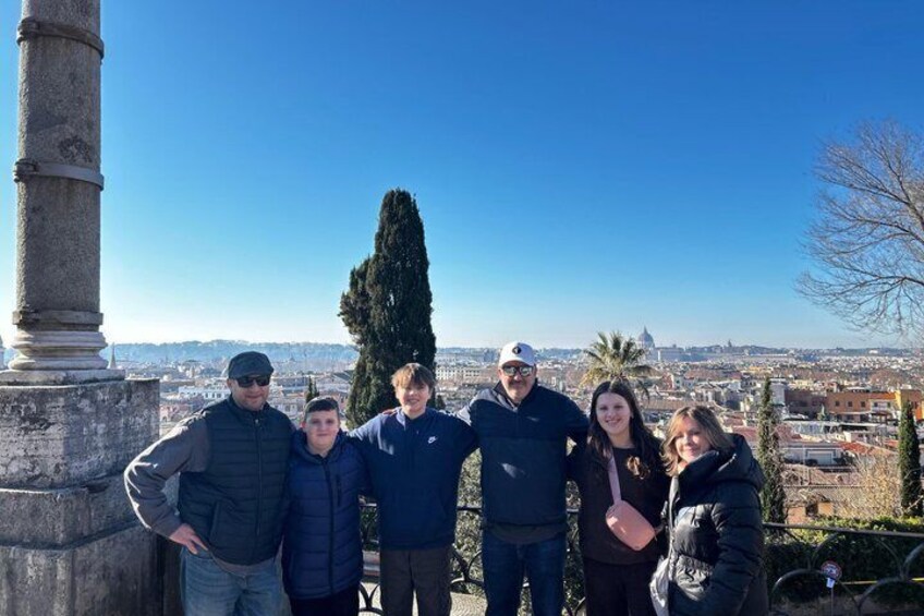 A group of people standing by a column with a cityscape in the background. 5