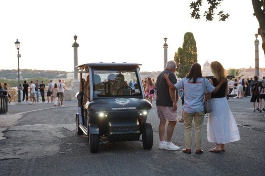 A black SUV parked on a paved area with people standing nearby. 2