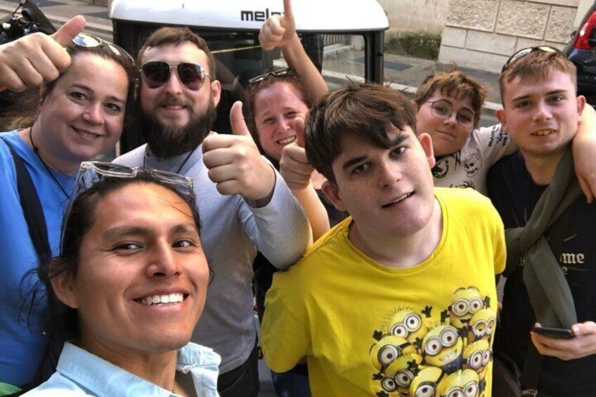 A group of people posing for a photo in front of a vehicle with the word 'mel' partially visible. 2
