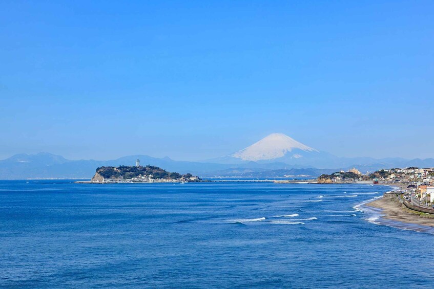 A coastal landscape with a prominent mountain in the background, calm sea, and a small island with buildings. 5