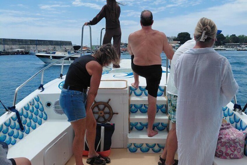 A group of people on a boat with a railing and a steering wheel. 4