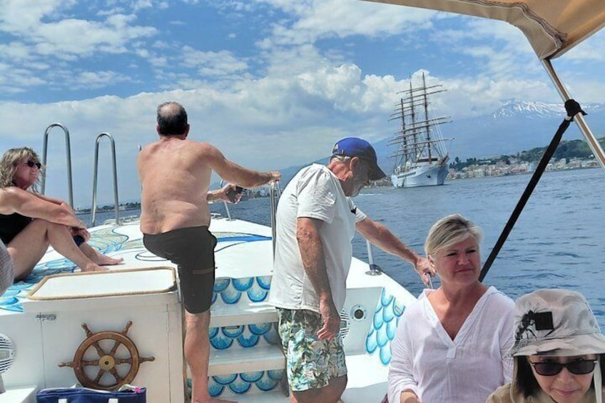 A group of people on a boat with a sailboat in the background. 3