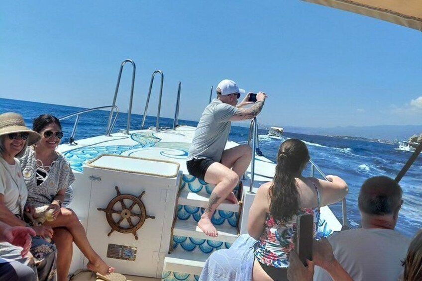 A group of people on a boat with a steering wheel and blue decorative elements. 2