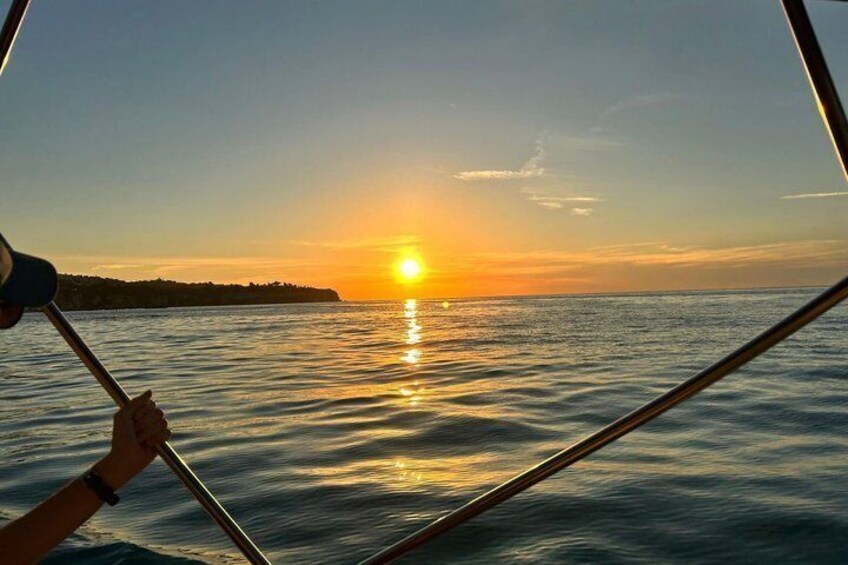 A sunset over calm water with a person rowing a boat. 3