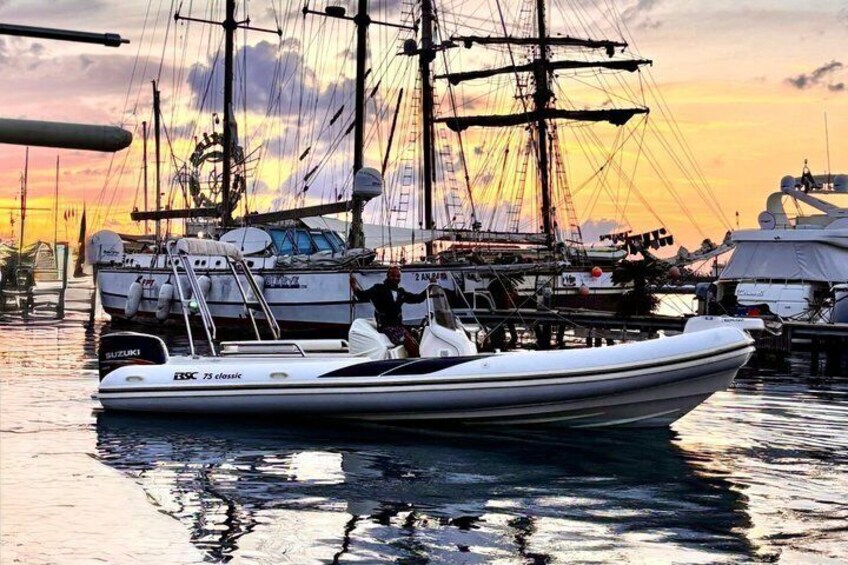 A sailboat docked at a marina with a sunset in the background. 1