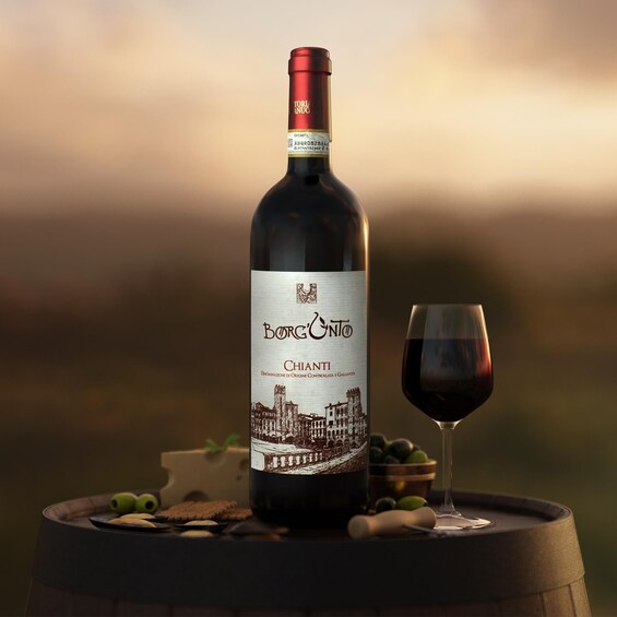 A bottle of Borgo Nero Chianti wine, a glass of red wine, and a barrel with grapes and olives on a table. 1