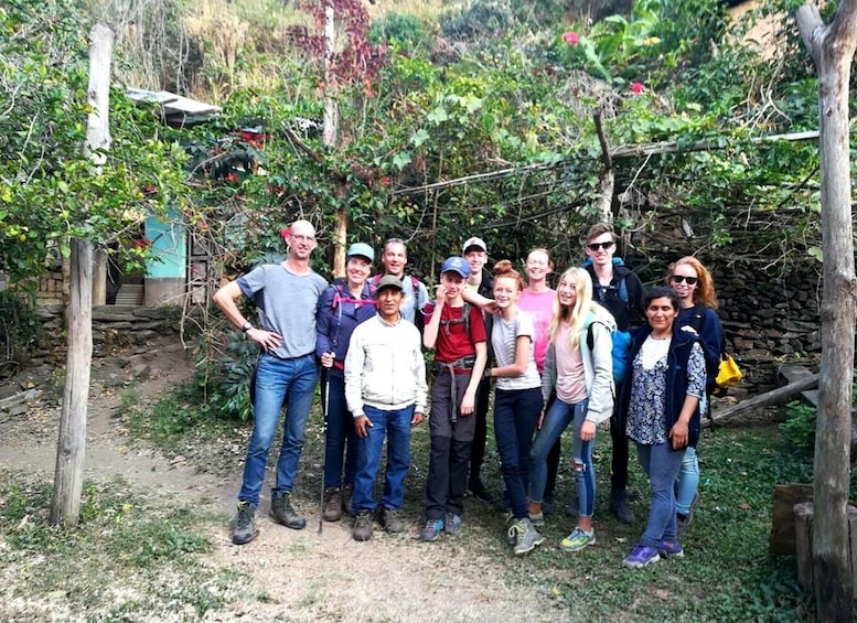 A group of people standing in a garden with a stone wall and wooden fence. 2