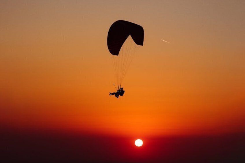 A parachutist descending during sunset. 4