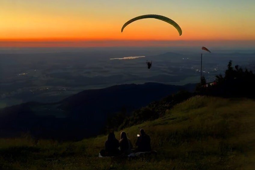 A person paragliding over a landscape at sunset. 3