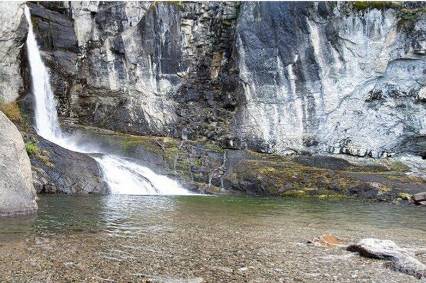 A waterfall cascading into a clear pool surrounded by rocky cliffs. 2