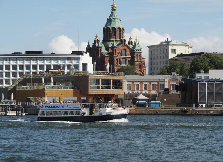 A boat named 'VALLISAAARI' on the water with a historic building in the background. 3