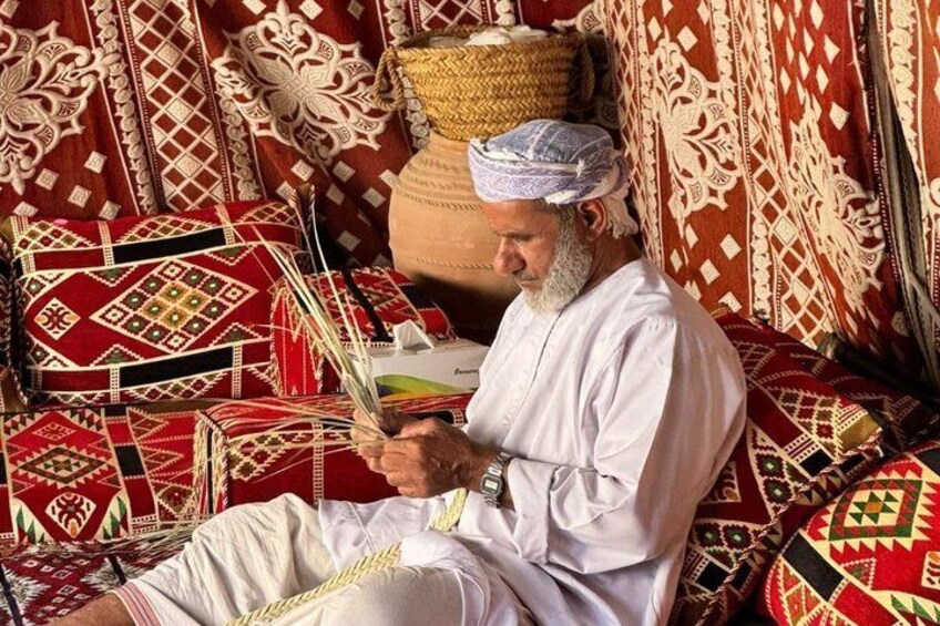 A man sitting on a patterned carpet, holding a book. 4