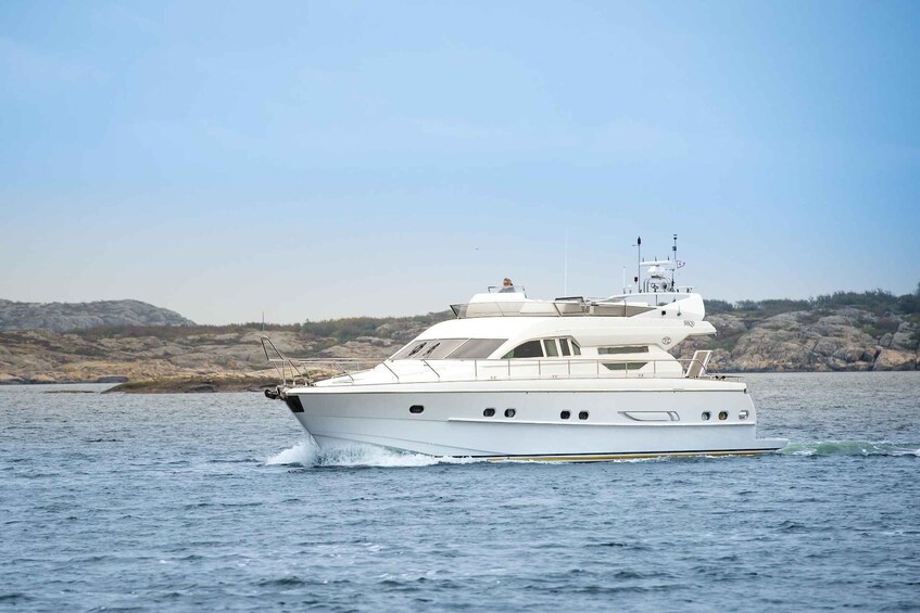 A white yacht on calm waters with a rocky shoreline in the background. 1