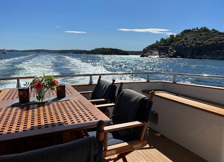 A boat deck with a table, chairs, and a vase of flowers. 3