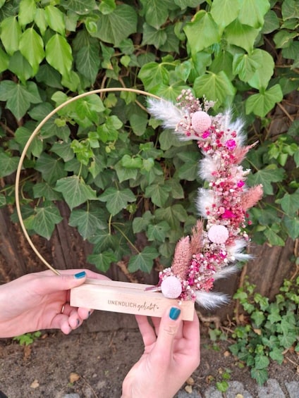 A hand holding a wooden box with a floral arrangement. 1