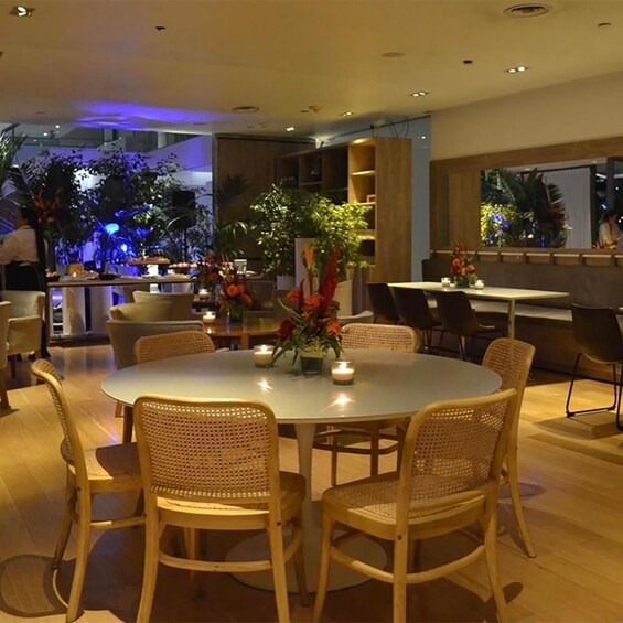 A restaurant with round tables, wicker chairs, and floral centerpieces. 5