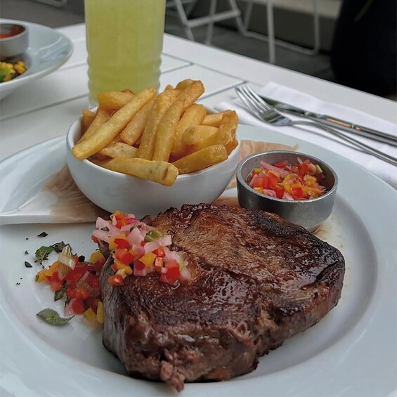 A plate with a steak, French fries, and a salsa garnish. 4