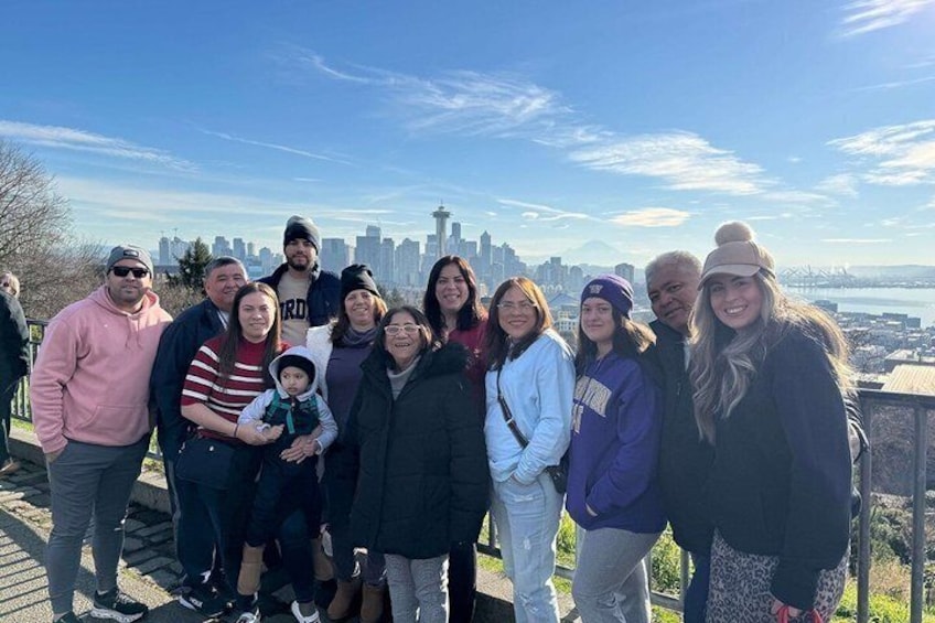 A group of people standing on a viewing platform with a city skyline in the background. 1