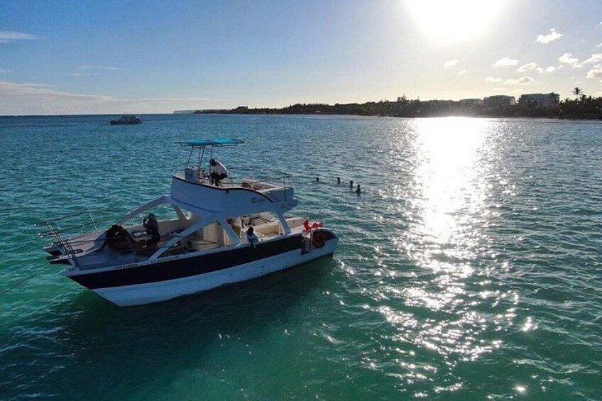 A boat on calm turquoise water with a clear sky and a distant shoreline. 2