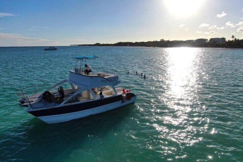 A boat on calm turquoise water with a clear sky and a distant shoreline. 2