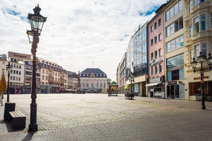 A cobblestone square with historic buildings, a lamppost, and a clear sky. 4