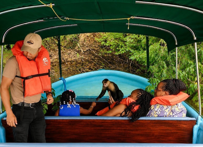 A boat with a green canopy, a man in a life jacket, and two women in orange life jackets. 3