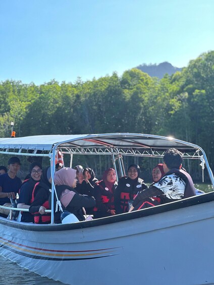 A group of people on a boat with a forested landscape in the background. 3