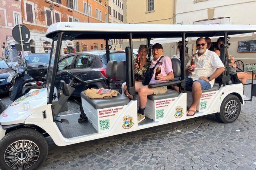 A golf cart with passengers, parked on a cobblestone street. 2