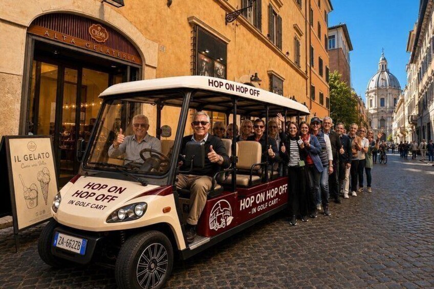 A golf cart with 'HOP ON HOP OFF' signage parked on a cobblestone street. 1