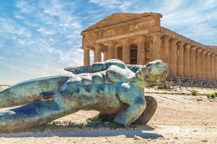 A large ancient Greek temple with columns and a bronze statue of a reclining figure. 2