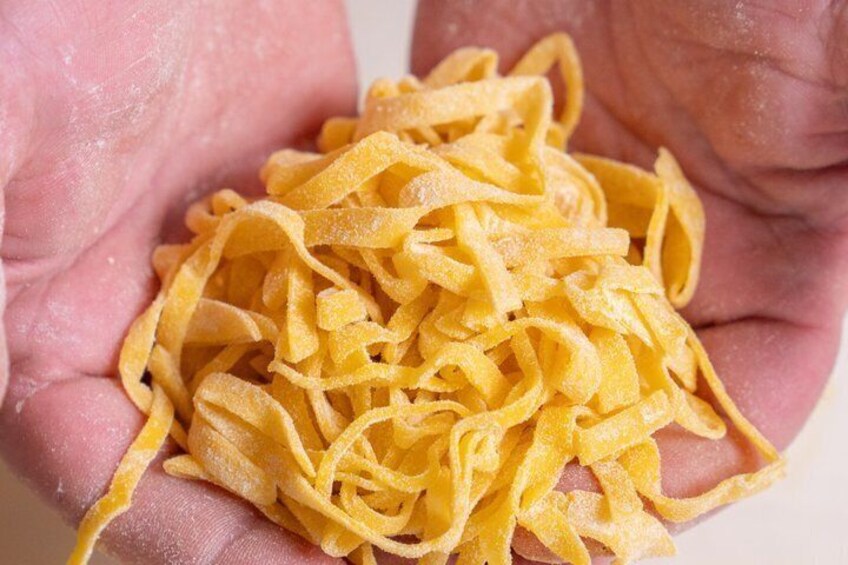 A hand holding a pile of yellow pasta. 2