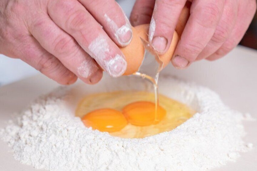 Hands cracking an egg into flour. 5