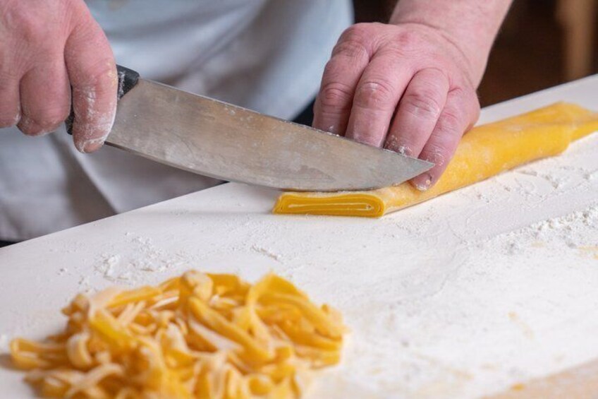 A person cutting pasta on a flour-dusted surface. 3