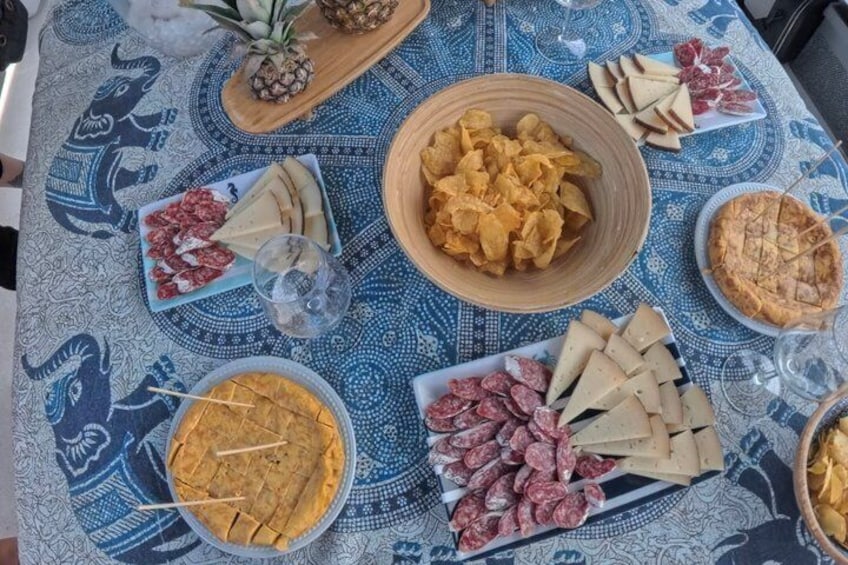 A table with various food items including chips, cheeses, and a pie. 2
