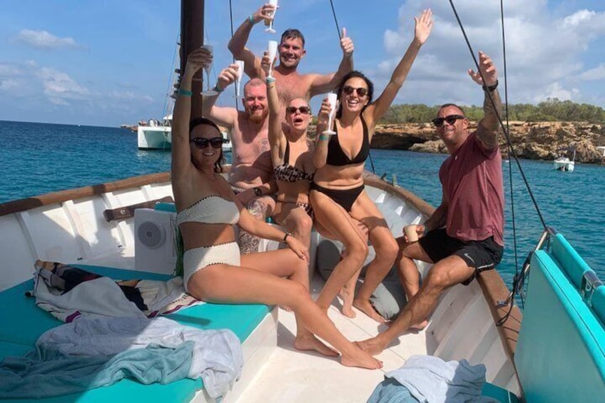 A group of people on a boat with the sea and rocky coastline in the background. 1