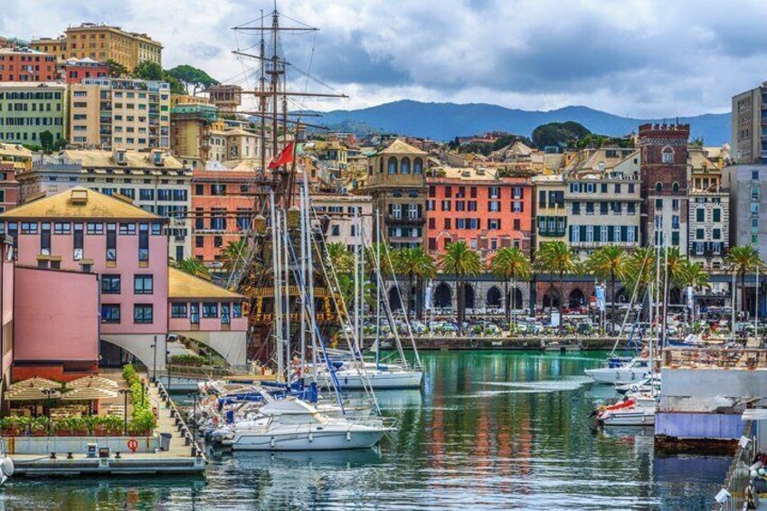 A marina with boats, colorful buildings, and a mountainous backdrop. 2