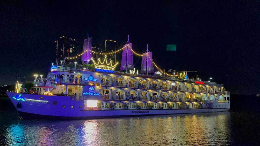 A brightly lit cruise ship with multiple decks and a festive decoration of purple and yellow lights. 2