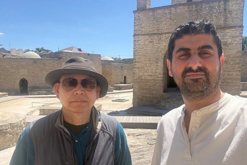 Two individuals standing in front of ancient stone structures with domed roofs. 5