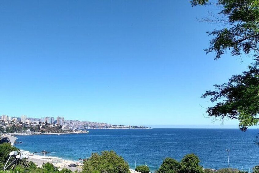 A coastal cityscape with a clear blue sky, a beach, and a distant shoreline. 3