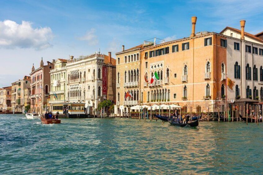 A canal with gondolas, historic buildings, and a boat. 5