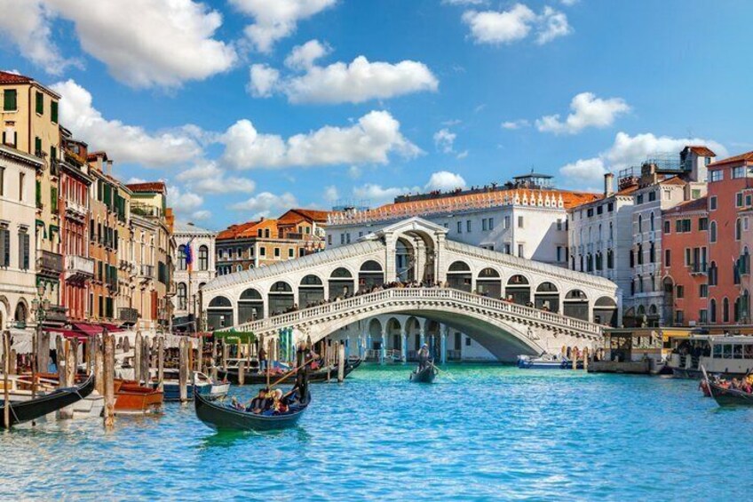 The Rialto Bridge in Venice, surrounded by colorful buildings and gondolas on the water. 2