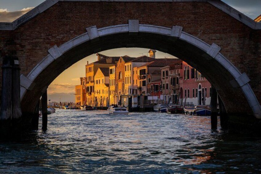 A stone bridge over water, historic buildings, and boats in a canal. 3