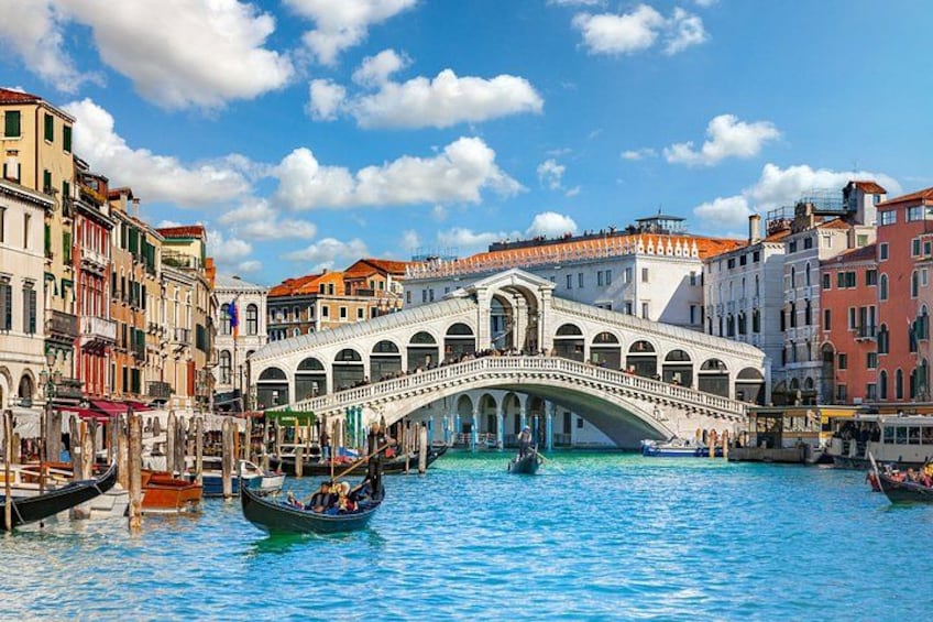 A historic bridge over a canal with gondolas, surrounded by colorful buildings. 2
