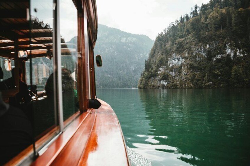 A wooden boat on calm water with a forested mountain in the background. 2