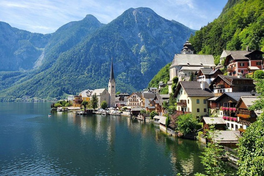 A lakeside village with a church, colorful houses, and mountains in the background. 1